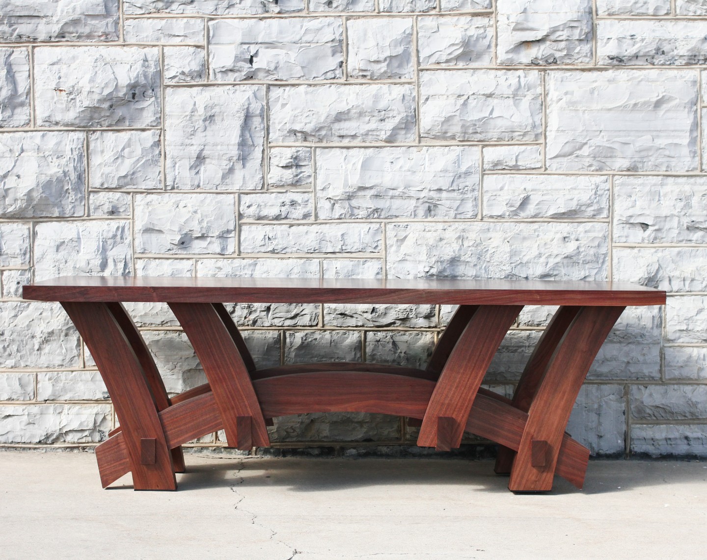 Walnut coffee table with arched legs against limestone wall